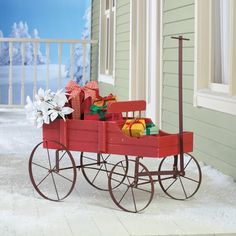 a blue wagon filled with presents sitting on top of snow covered ground next to a building