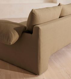 a tan couch with pillows on it in a living room or dining room area that is clean and ready for guests to use