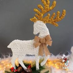 a white and gold reindeer with a bow on it's head