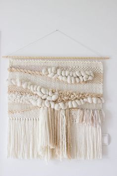 a wall hanging with white beads and tassels on the bottom half of it