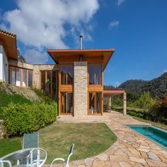 a house with a pool in front of it and some chairs around the outside area