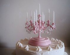 a white cake topped with a pink frosted icing chandelier and candles