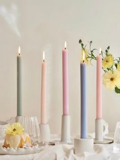 three candles are sitting next to each other on a table with flowers in the background