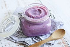 a glass jar filled with purple paste next to a wooden spoon