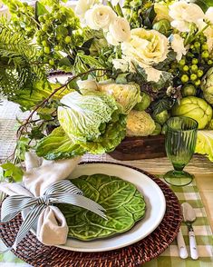 there is a table setting with green and white flowers