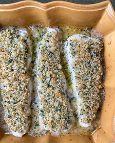 three fish fillets in a yellow dish with seasoning sprinkled on top