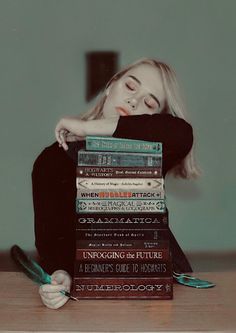 a woman sitting on top of a stack of books with her eyes closed next to a pile of books