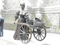 a statue of a woman pushing a cart with baskets on it