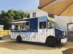 a blue and white food truck parked in front of a building with an awning