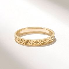 a yellow gold wedding band with sunflowers on the inside and outside, set against a plain white background