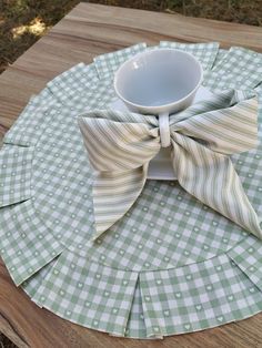 a cup and saucer sitting on top of a wooden table with a bow tie around it