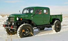 an old green truck is parked in the snow