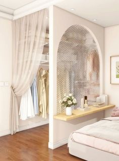 a bedroom with white walls and wooden floors, an arched window over the bed has pink pillows on it