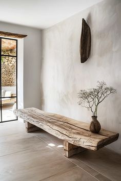 a wooden bench sitting in front of a window next to a vase filled with flowers