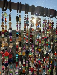 many different colored beads hanging from the side of a window with sun shining through them