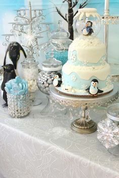 a table topped with a cake covered in frosting and penguin figurines on top of it