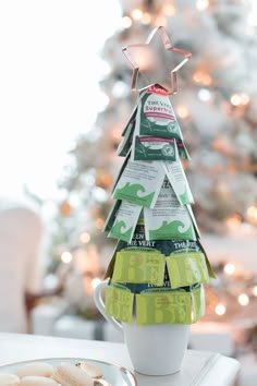 a christmas tree made out of coffee cups on a table next to a plate with cookies