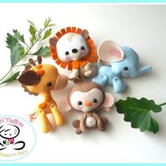 four small stuffed animals sitting next to each other on a white surface with green leaves