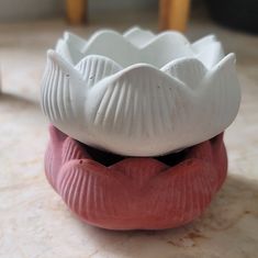 two white and pink vases sitting on top of a table