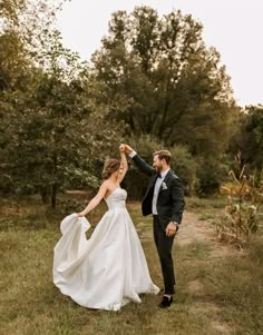 a bride and groom dancing in the woods