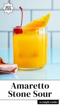 an orange drink in a glass with a cherry garnish