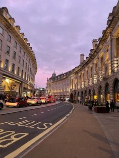 an empty city street at dusk with cars parked on both sides and buildings in the background