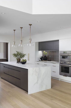 a large kitchen with marble counter tops and an island in front of two ovens