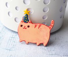 a pink cat with a party hat on it's head