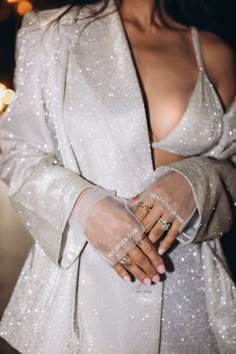 a woman in a white dress and jacket holding her hands together