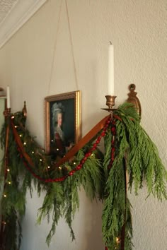 christmas garland hanging on the wall next to a candle holder with a portrait in it