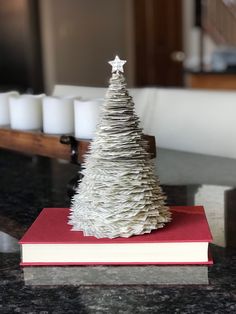 a small white christmas tree sitting on top of a red book