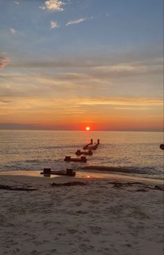 the sun is setting over the water at the beach