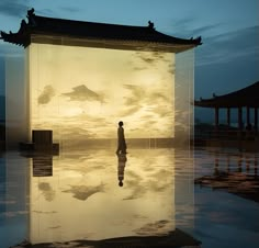 a person standing in front of a large screen with the sky reflected on it's surface