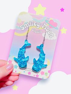 a pair of blue earrings with polka dots on them, sitting in front of a pink background