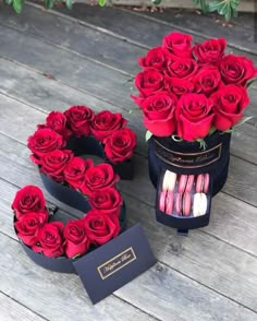 two boxes with roses and macaroons in them sitting on a wooden floor next to each other