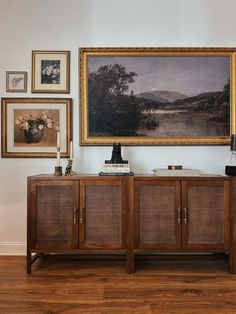 a painting hangs on the wall next to a sideboard