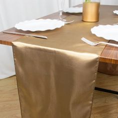 the table is set with white plates and silverware, along with a gold cloth draped over it