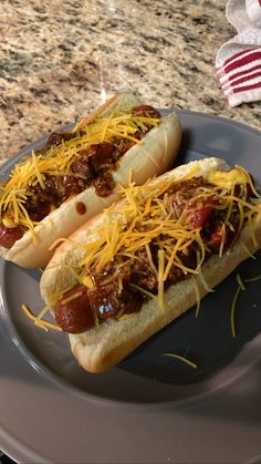 two hot dogs covered in chili and cheese on a plate