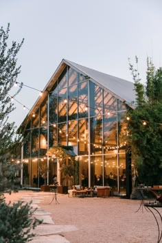 a large glass building with lots of lights on it's sides and trees in the background