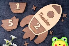 a wooden calendar with a rocket and stars on it, next to a frog toy