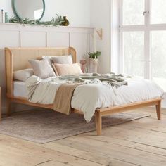 a bed sitting on top of a wooden floor next to a white wall and window