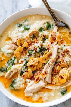 a white bowl filled with chicken, rice and spinach on top of a table