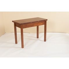 a small wooden table sitting on top of a white sheet covered floor next to a wall