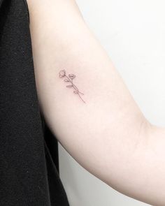 a woman's arm with a single flower tattoo on the left side of her arm