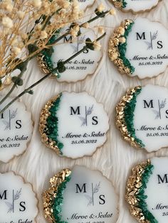 wedding cookies decorated with gold and green frosting are displayed on a white tablecloth