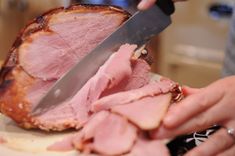 a person is cutting meat with a large knife