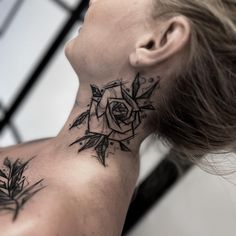 a woman's neck with a rose and leaves tattoo on her left side ribcage