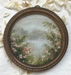 there is a painting in the frame on the table cloth with white flowers around it