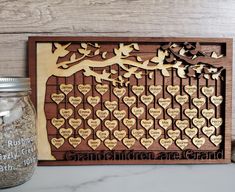 a wooden family tree with many names and hearts on it, next to a jar of sand