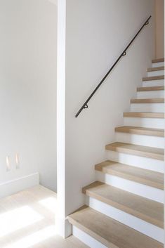 there is a stair case in the room with white walls and wood floors, along with two lights on either side of the stairs